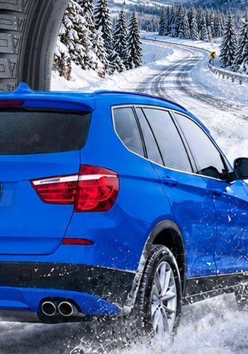 A blue SUV driving through snow with Sailun winter tires.